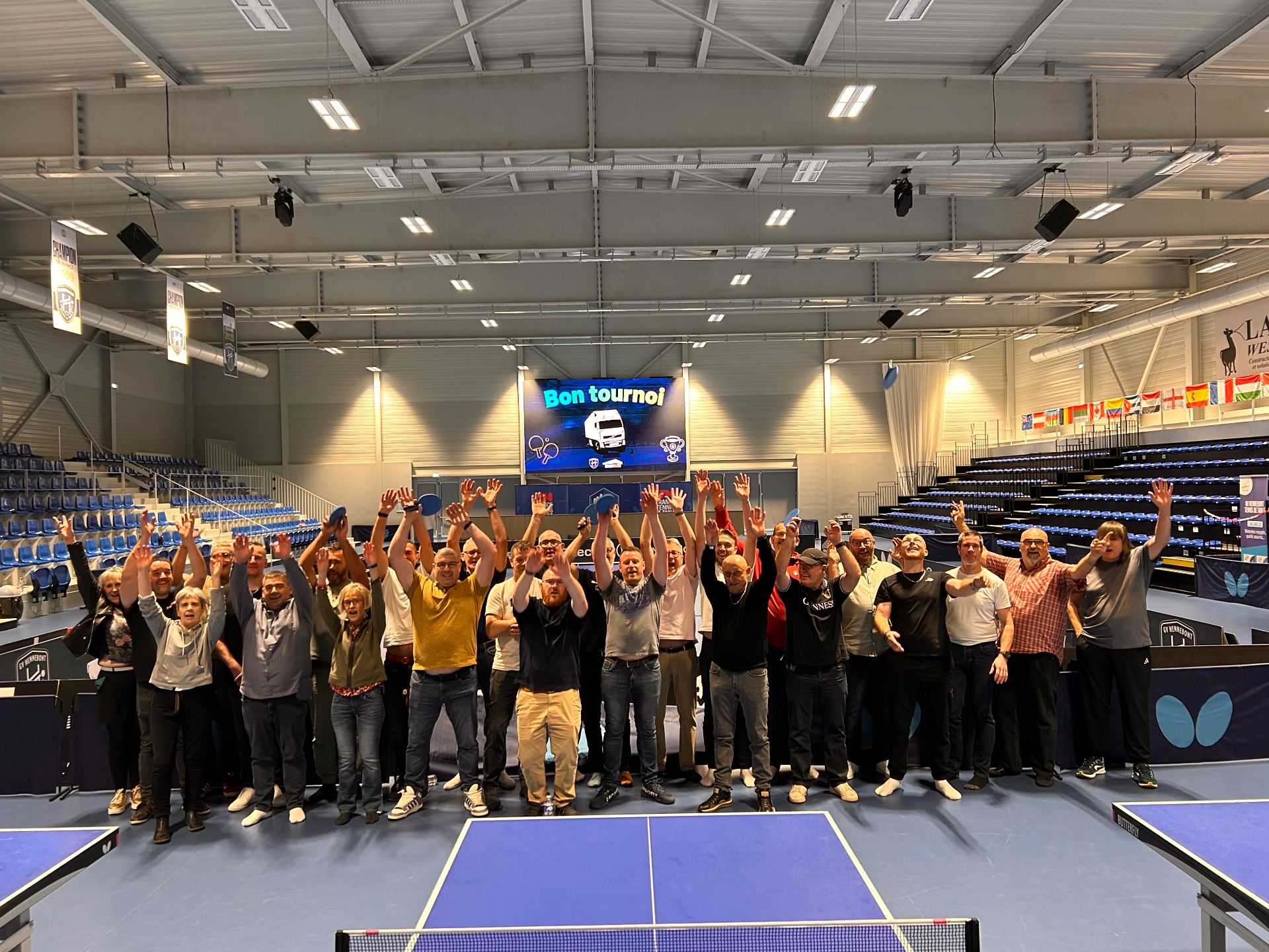 Esprit d'équipe et médailles du travail : une journée de convivialité chez les Transports Poulain Photo de groupe des collaborateurs des Transports Poulain au Ping Center d'Hennebont, bras levés lors du tournoi de tennis de table