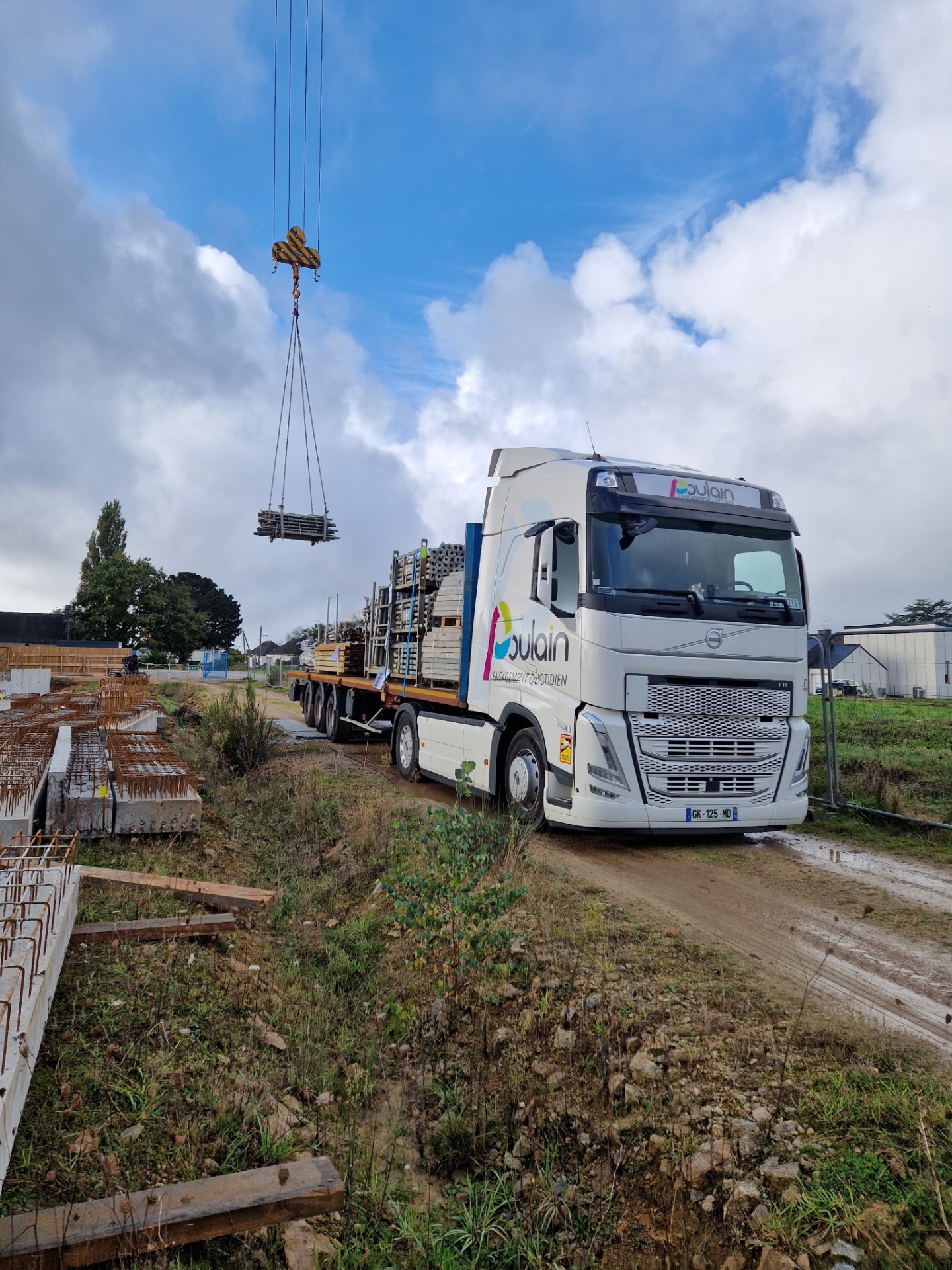 Semi-plateau Volvo Poulain en chargement sur chantier à la grue